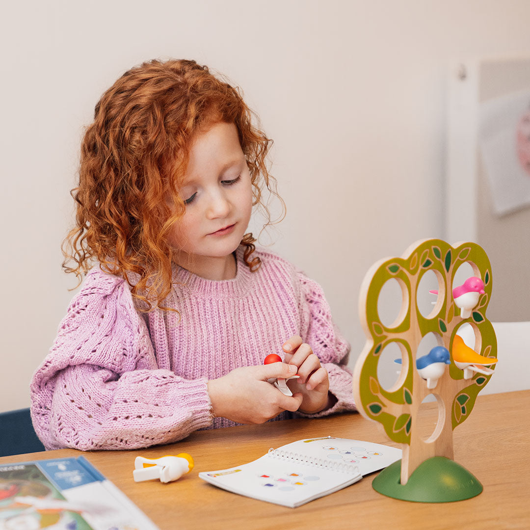 Photo of child playing 5 Little Birds while sitting at a table.