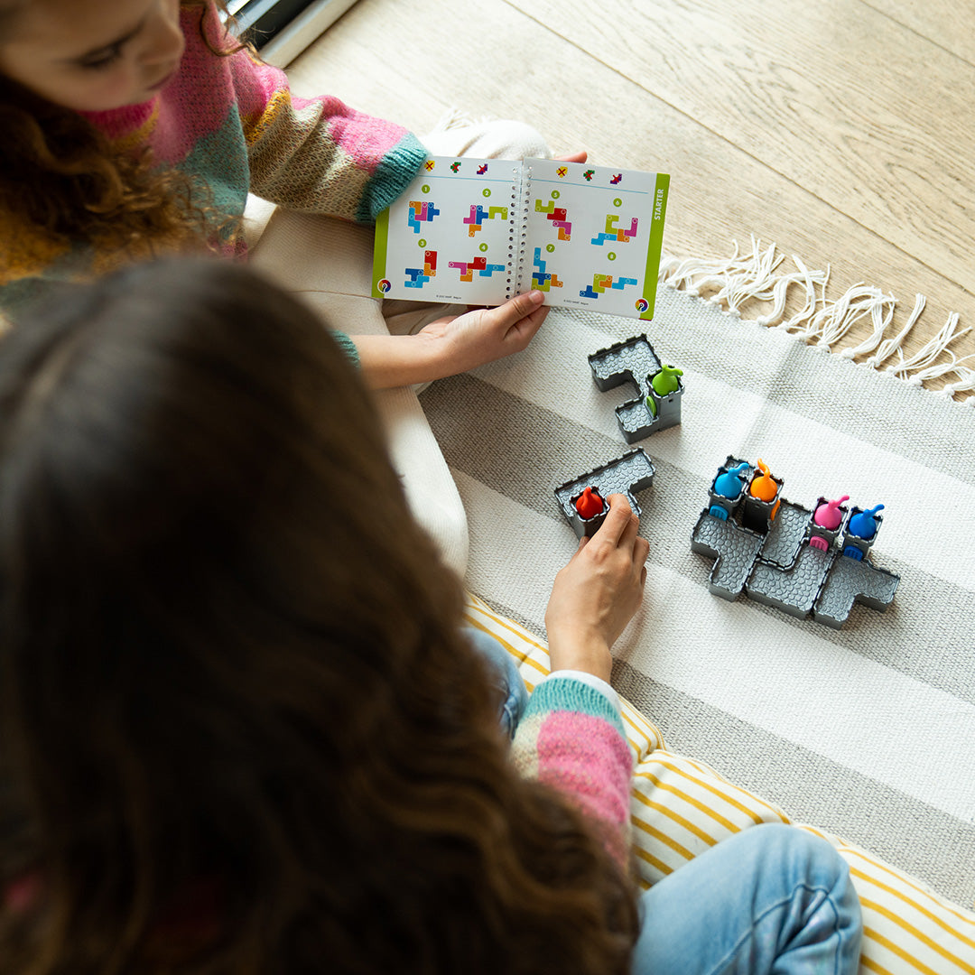 Photo of two children sitting on the floor playing the Tower Stacks mind puzzle by Smart Games.